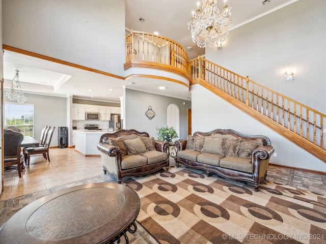 living room with crown molding, a towering ceiling, a chandelier, and a raised ceiling