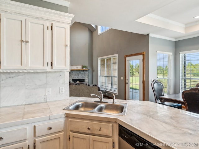 kitchen with tasteful backsplash, sink, tile counters, a fireplace, and dishwasher