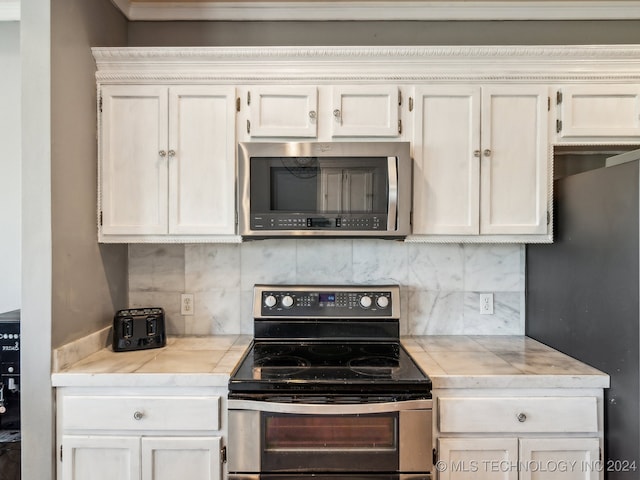 kitchen featuring stainless steel appliances, backsplash, and white cabinets