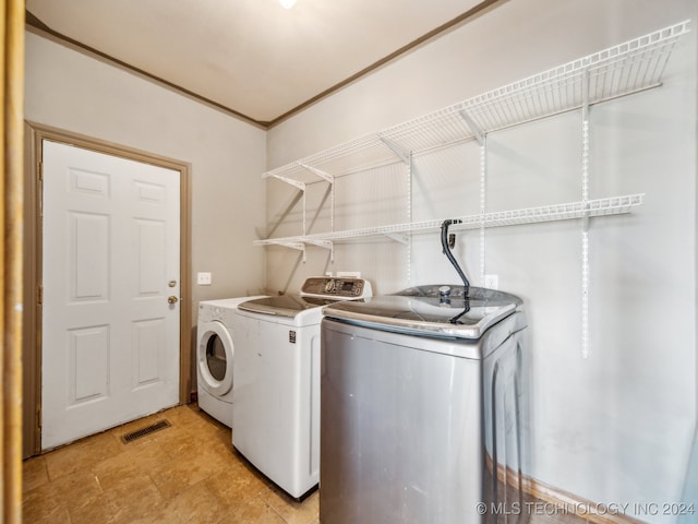 washroom with ornamental molding and washer and dryer