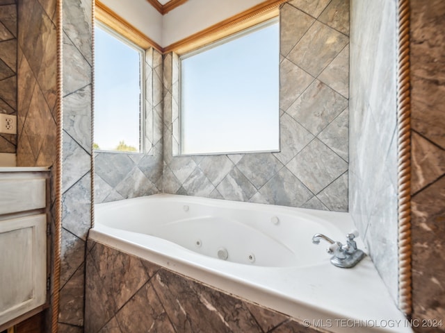 bathroom with crown molding and tiled tub