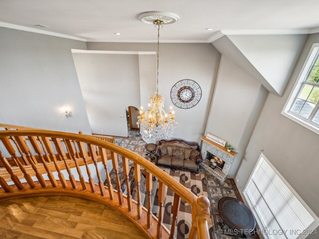 stairs featuring a brick fireplace, crown molding, a chandelier, and hardwood / wood-style flooring