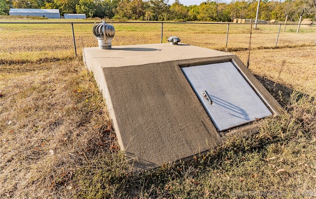 entry to storm shelter featuring a yard and a rural view