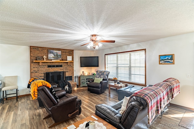 living room with a brick fireplace, ceiling fan, hardwood / wood-style floors, and a textured ceiling