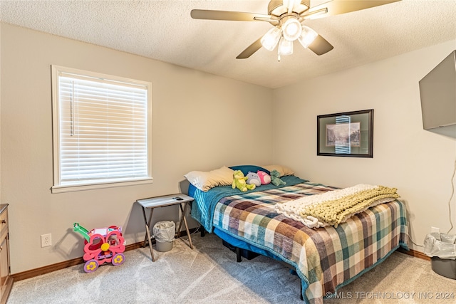 carpeted bedroom featuring ceiling fan and a textured ceiling