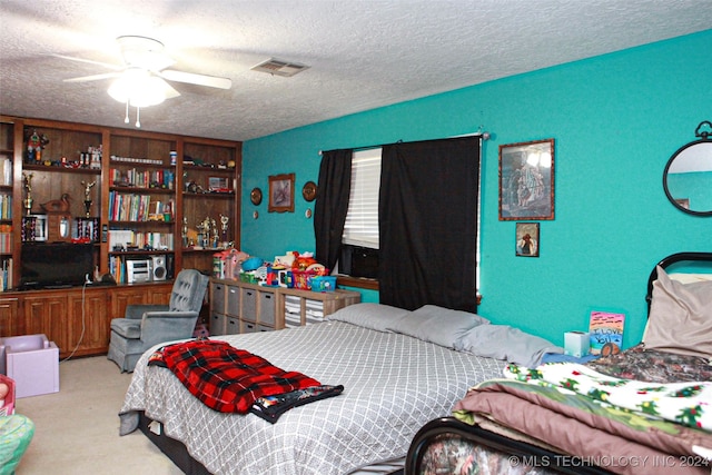 carpeted bedroom featuring ceiling fan and a textured ceiling