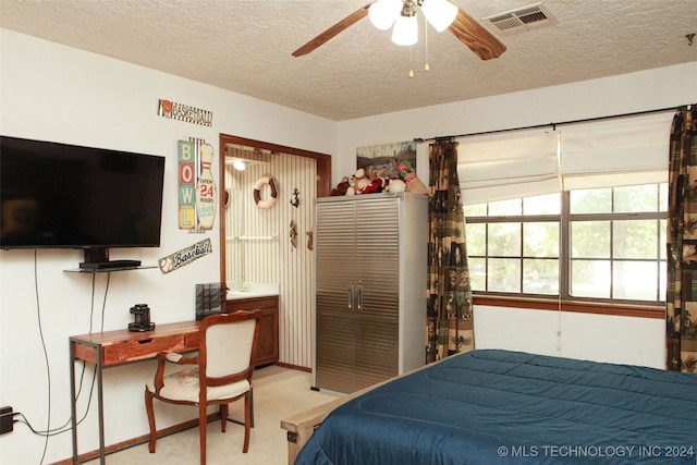 bedroom with ceiling fan, light colored carpet, a textured ceiling, and a closet