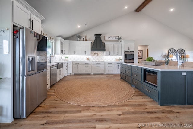 kitchen featuring white cabinets, light hardwood / wood-style flooring, appliances with stainless steel finishes, beam ceiling, and backsplash