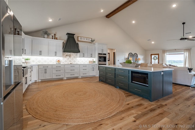 kitchen featuring premium range hood, light hardwood / wood-style flooring, built in microwave, and white cabinetry