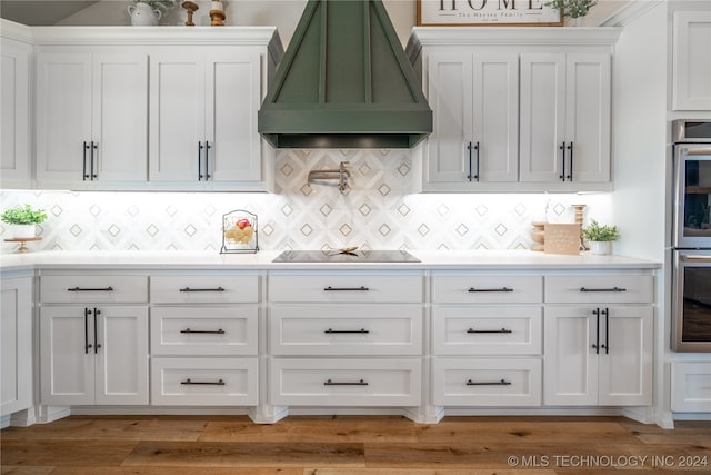 kitchen with black electric cooktop, white cabinets, wood-type flooring, and custom exhaust hood