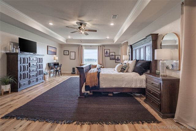 bedroom featuring crown molding, ceiling fan, a tray ceiling, and light hardwood / wood-style floors