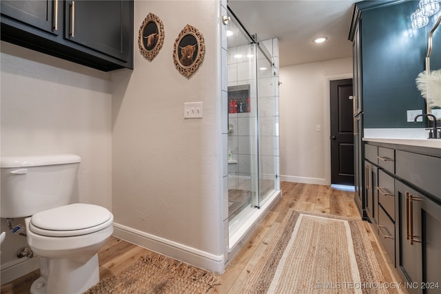 bathroom with vanity, toilet, a shower with door, and hardwood / wood-style flooring