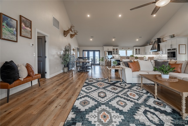 living room with light wood-type flooring, high vaulted ceiling, and ceiling fan