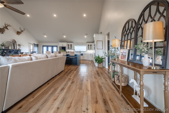 living room with ceiling fan, light hardwood / wood-style flooring, and high vaulted ceiling