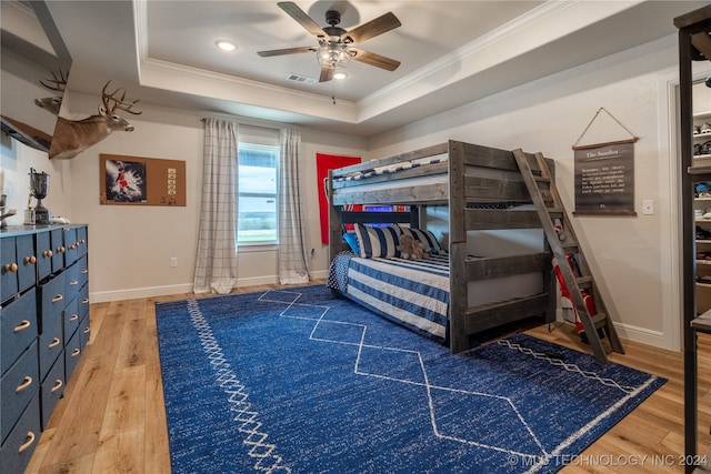 bedroom with ornamental molding, ceiling fan, hardwood / wood-style floors, and a raised ceiling