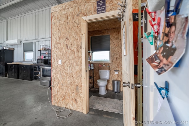 interior space with a wall mounted air conditioner, toilet, and concrete flooring