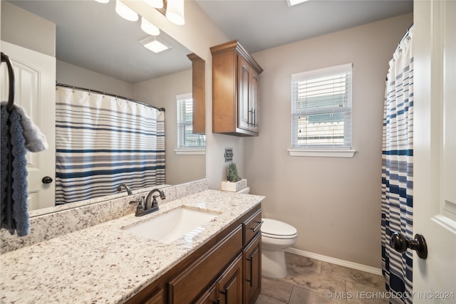 bathroom featuring plenty of natural light, tile patterned floors, vanity, and toilet