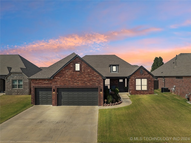 view of front of property featuring cooling unit, a garage, and a yard