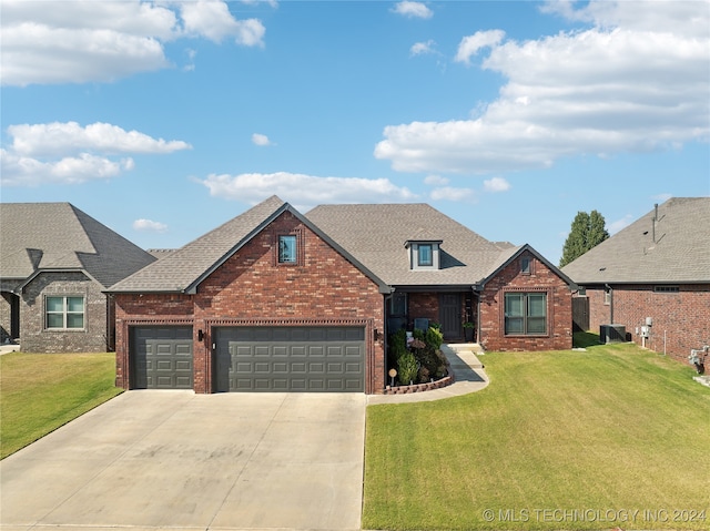 view of front of property featuring a garage, cooling unit, and a front lawn