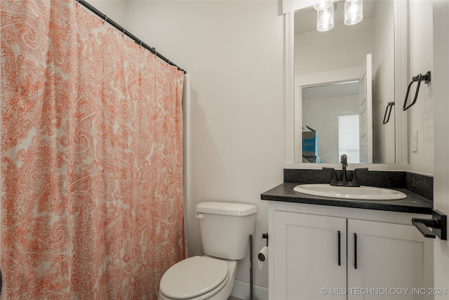 bathroom with walk in shower, vanity, and toilet