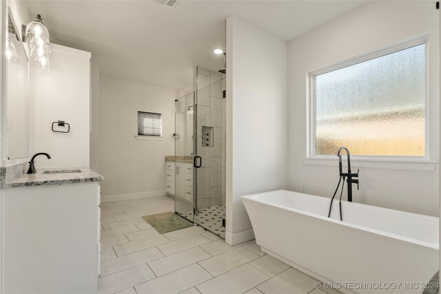 bathroom with tile patterned floors, vanity, and shower with separate bathtub