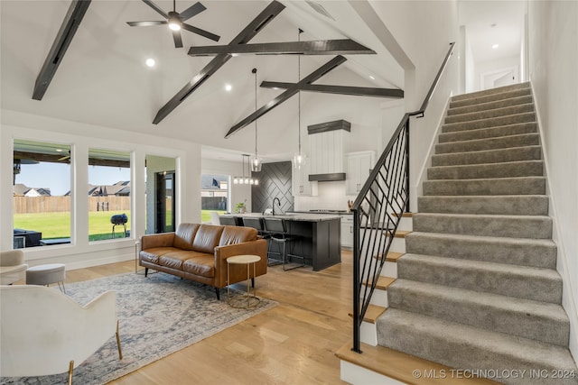 living room with ceiling fan, sink, beam ceiling, high vaulted ceiling, and light hardwood / wood-style floors