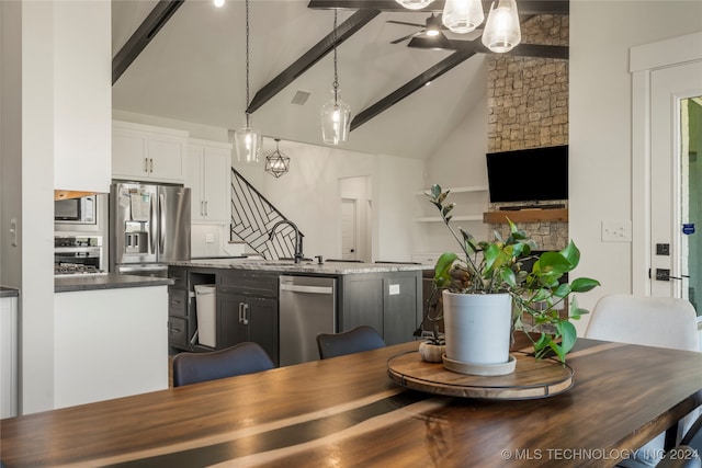 dining area featuring a stone fireplace, beamed ceiling, sink, and high vaulted ceiling