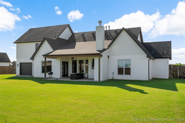 rear view of house with ceiling fan, a garage, a lawn, and a patio area