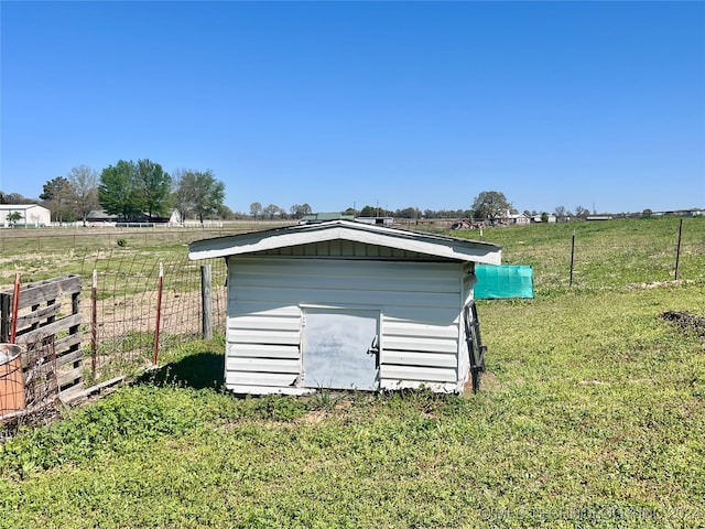 view of outbuilding featuring a rural view and a lawn