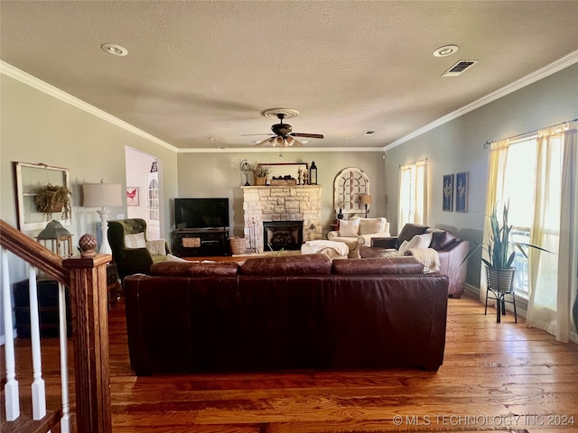 living room featuring ornamental molding, a stone fireplace, dark hardwood / wood-style flooring, and ceiling fan