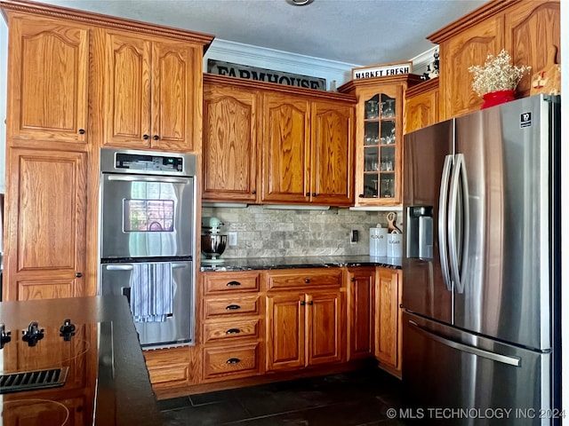 kitchen featuring dark tile patterned floors, crown molding, stainless steel appliances, and backsplash