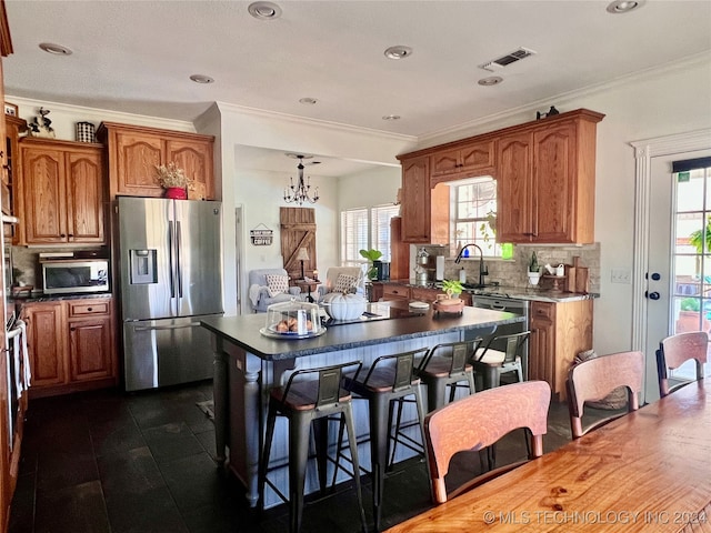 kitchen with appliances with stainless steel finishes, a kitchen island, a wealth of natural light, and decorative backsplash