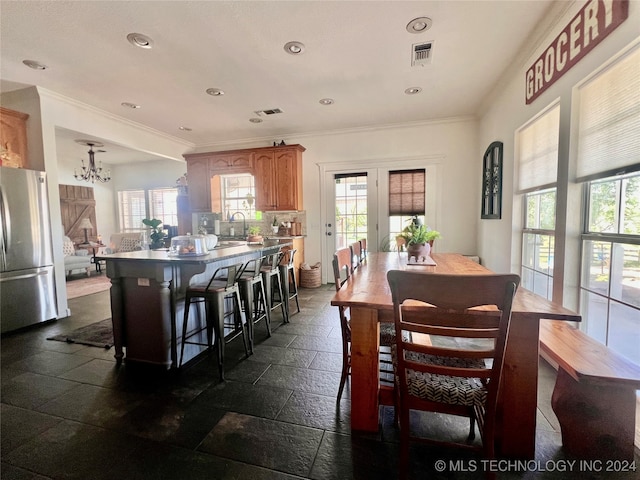 dining room featuring a healthy amount of sunlight, crown molding, french doors, and an inviting chandelier