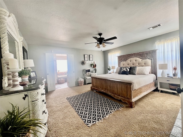 carpeted bedroom with ceiling fan, a textured ceiling, and ensuite bathroom