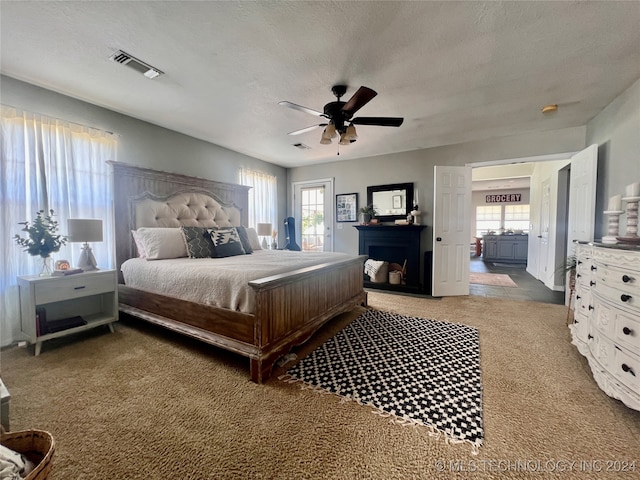 bedroom featuring a textured ceiling, carpet floors, multiple windows, and ceiling fan