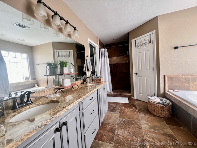 bathroom with a textured ceiling, vanity, and independent shower and bath