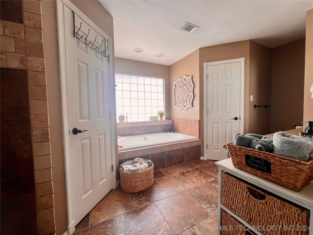 bathroom featuring tiled bath and a textured ceiling