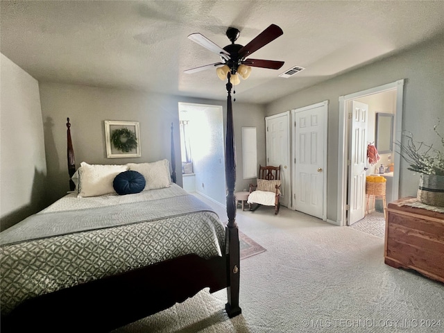 carpeted bedroom with ceiling fan, two closets, and a textured ceiling