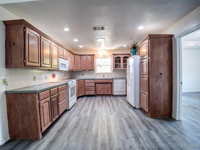 kitchen with white appliances, sink, wood-type flooring, and tasteful backsplash