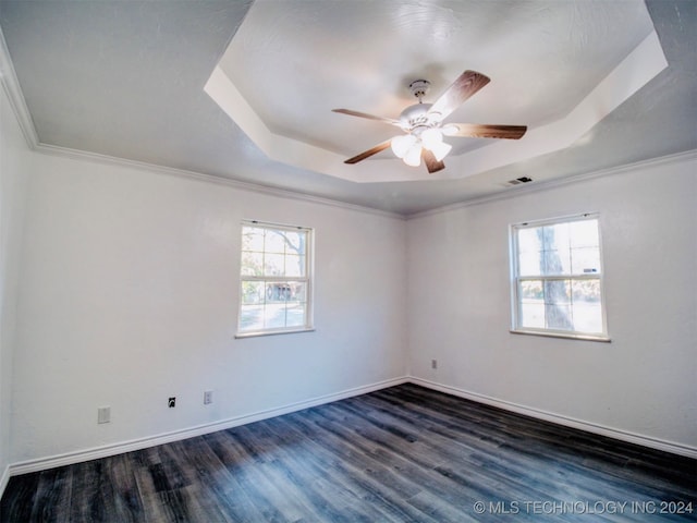 empty room with crown molding, ceiling fan, dark wood-type flooring, and a tray ceiling