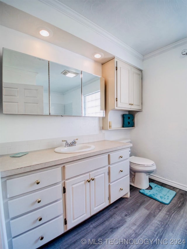 bathroom with ornamental molding, toilet, vanity, and wood-type flooring