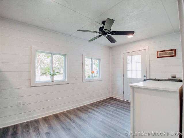 empty room featuring dark wood-type flooring, wooden walls, and ceiling fan