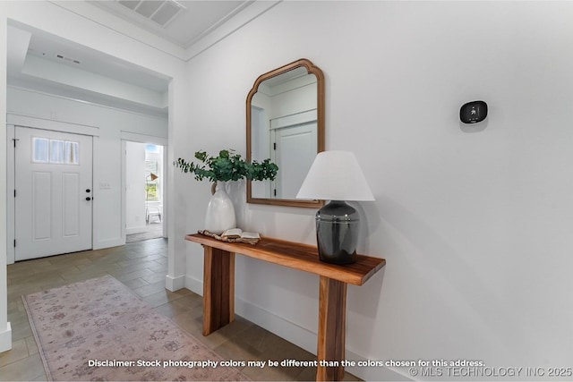 foyer entrance with visible vents, crown molding, and baseboards