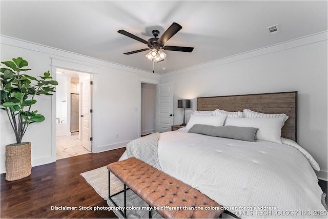 bedroom with visible vents, dark wood-type flooring, ornamental molding, ensuite bath, and baseboards