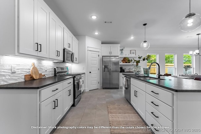 kitchen featuring appliances with stainless steel finishes, dark countertops, white cabinetry, and pendant lighting