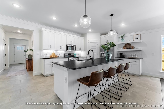 kitchen with stainless steel appliances, a sink, tasteful backsplash, dark countertops, and open shelves