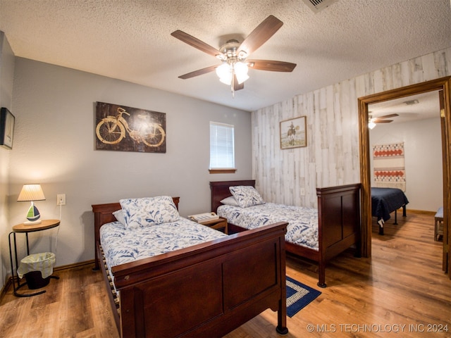 bedroom with ceiling fan, hardwood / wood-style flooring, and a textured ceiling