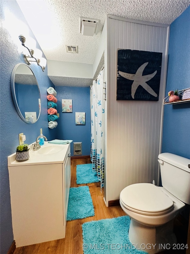 bathroom with vanity, toilet, wood-type flooring, and a textured ceiling