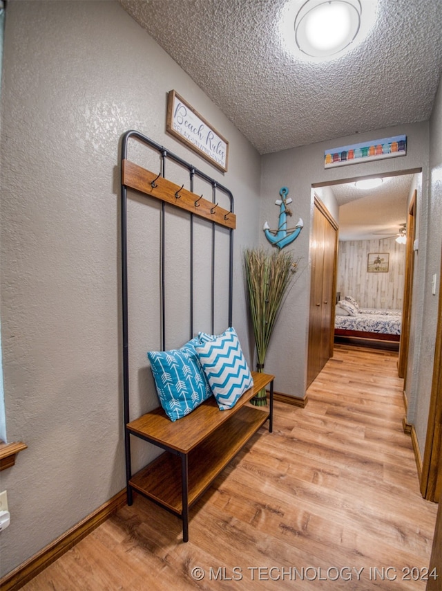 hallway with a textured ceiling and light wood-type flooring