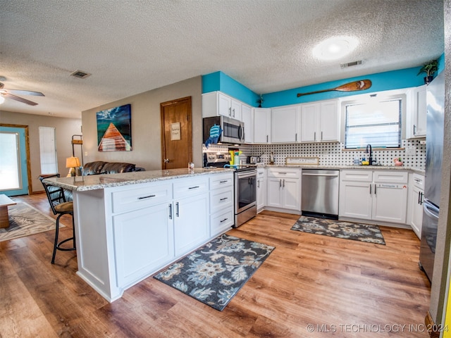 kitchen with white cabinets, a breakfast bar area, appliances with stainless steel finishes, and kitchen peninsula